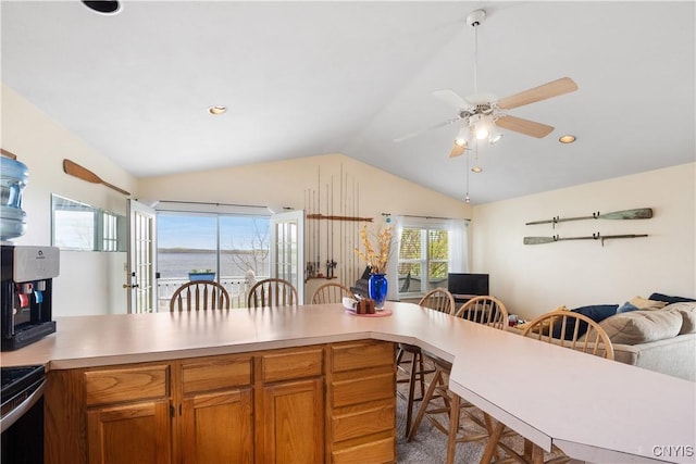 kitchen featuring electric range, a kitchen bar, light countertops, a ceiling fan, and vaulted ceiling