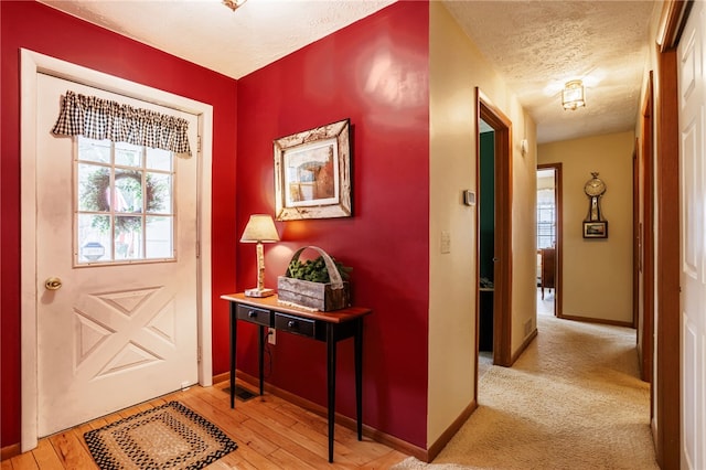 entryway featuring plenty of natural light, a textured ceiling, light wood finished floors, and baseboards