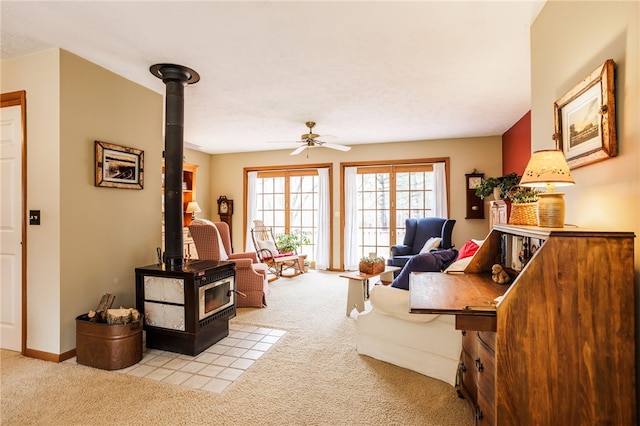 living room featuring carpet flooring, ceiling fan, and a wood stove