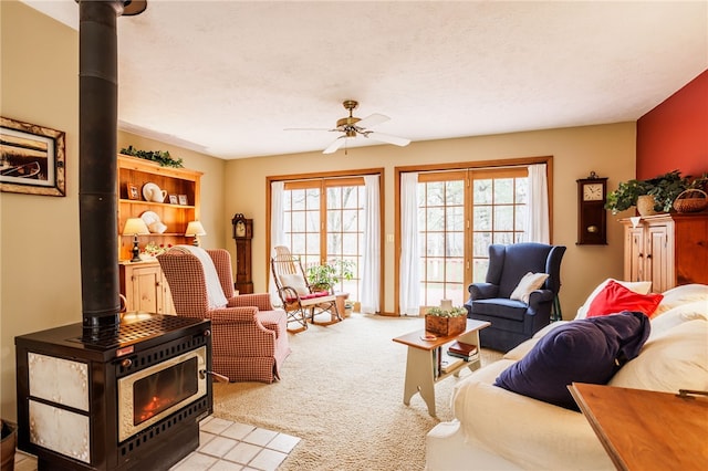 living area with ceiling fan, carpet, and a wood stove