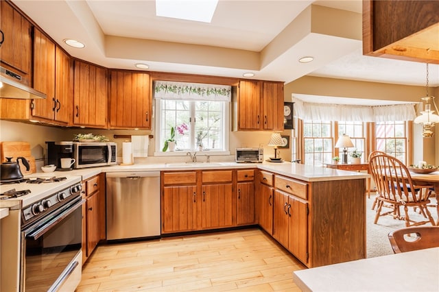 kitchen featuring a sink, appliances with stainless steel finishes, a peninsula, and light countertops