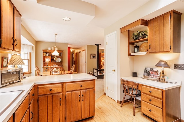 kitchen featuring light countertops, light wood-type flooring, a peninsula, and built in desk