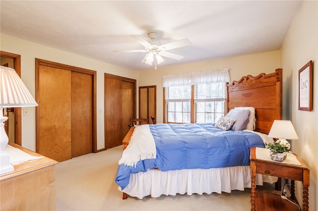 carpeted bedroom featuring ceiling fan and multiple closets