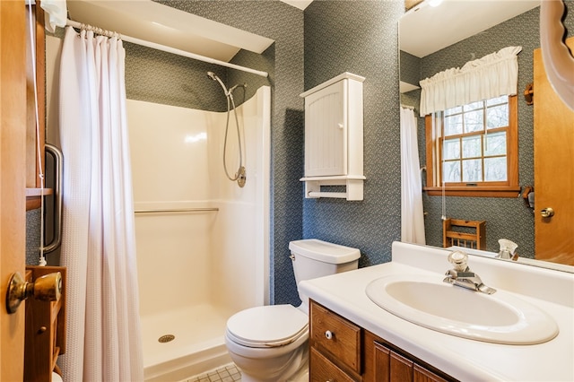 bathroom featuring vanity, wallpapered walls, toilet, and a shower stall