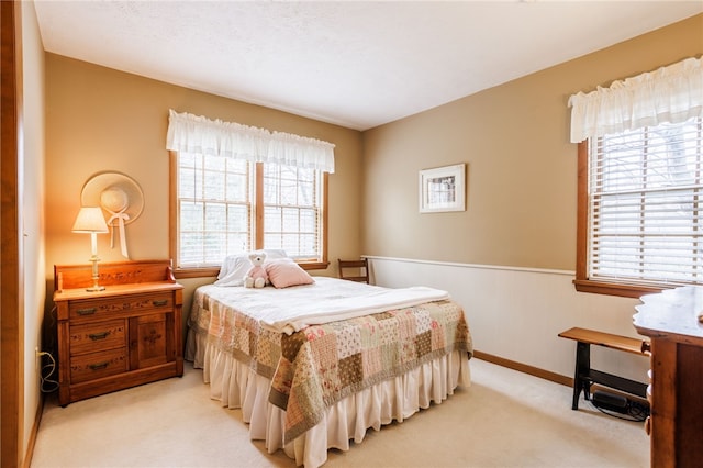bedroom with baseboards and light colored carpet