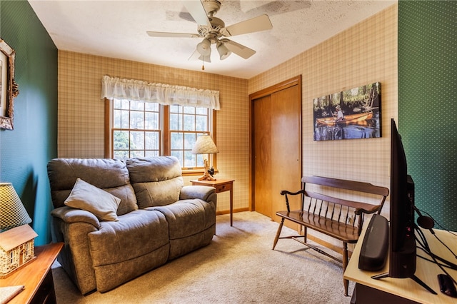 sitting room featuring carpet floors, a ceiling fan, baseboards, and wallpapered walls