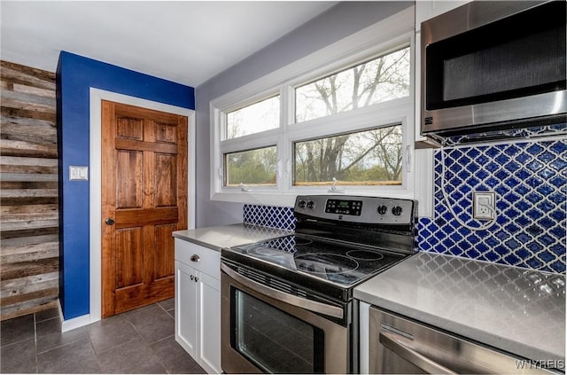 kitchen with white cabinets, appliances with stainless steel finishes, light countertops, decorative backsplash, and dark tile patterned floors