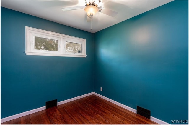 unfurnished room with baseboards, ceiling fan, dark wood finished floors, and visible vents