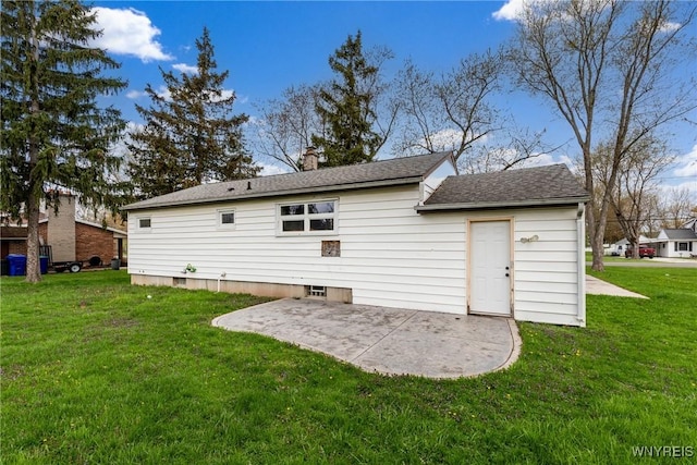 back of house with a lawn, a shingled roof, a patio area, and a chimney