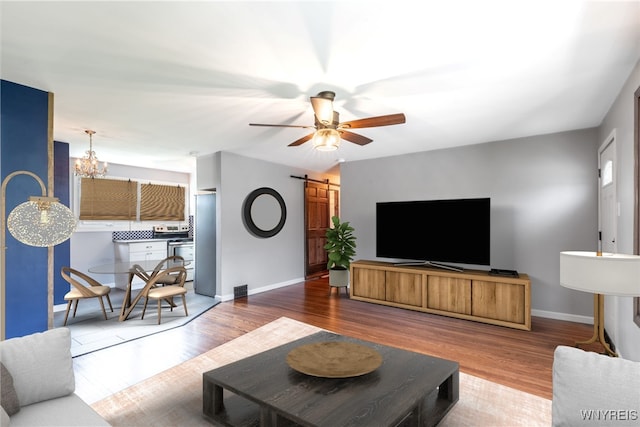 living room with baseboards, a barn door, and wood finished floors