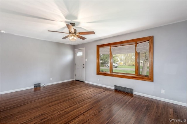 empty room featuring baseboards, visible vents, ceiling fan, and dark wood-type flooring