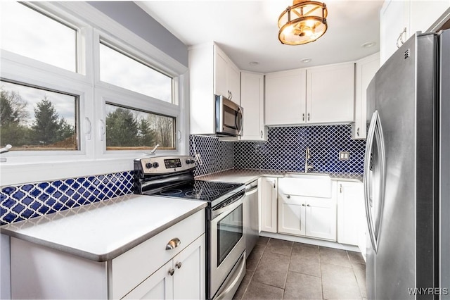 kitchen featuring a sink, decorative backsplash, dark tile patterned flooring, and stainless steel appliances