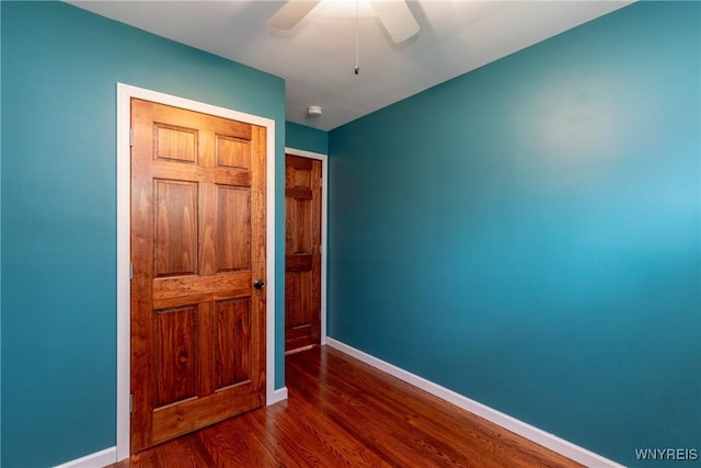 unfurnished bedroom with baseboards, ceiling fan, wood finished floors, and a closet