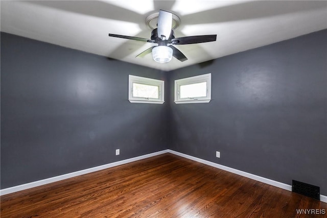 unfurnished room featuring dark wood-style flooring, a ceiling fan, baseboards, and visible vents