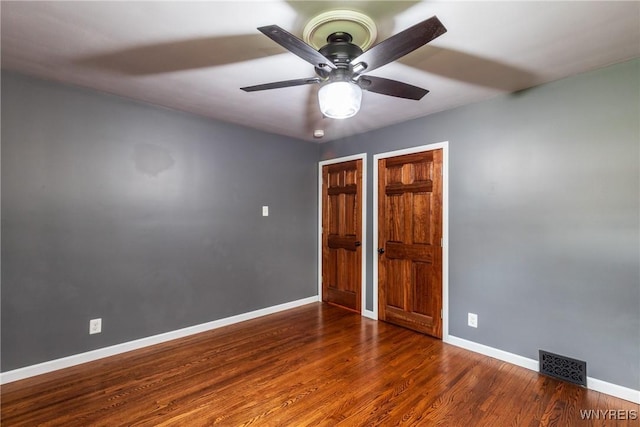 unfurnished bedroom with a ceiling fan, baseboards, visible vents, and wood finished floors