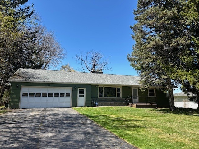 single story home with an attached garage, aphalt driveway, a chimney, and a front yard