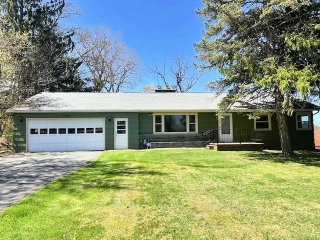 ranch-style house with covered porch, an attached garage, a front lawn, and aphalt driveway