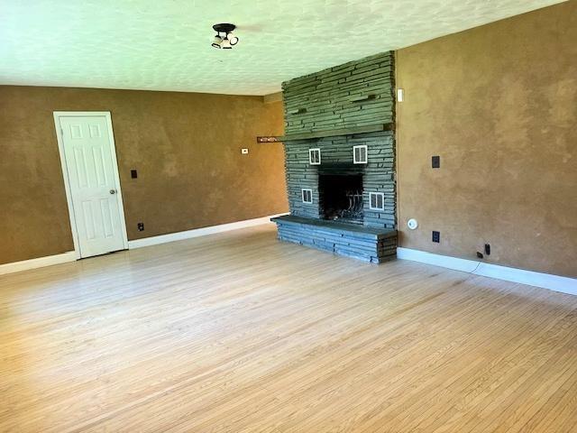 unfurnished living room featuring baseboards, wood finished floors, and a fireplace
