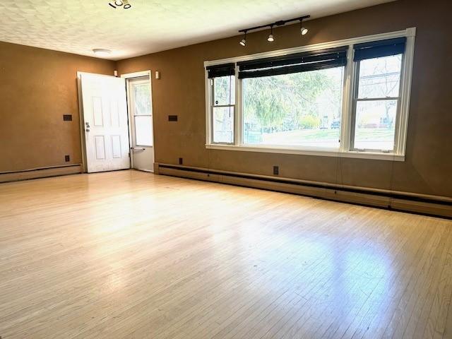 interior space featuring a baseboard heating unit, track lighting, wood finished floors, and a baseboard radiator