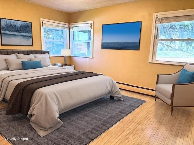 bedroom with baseboard heating and wood finished floors