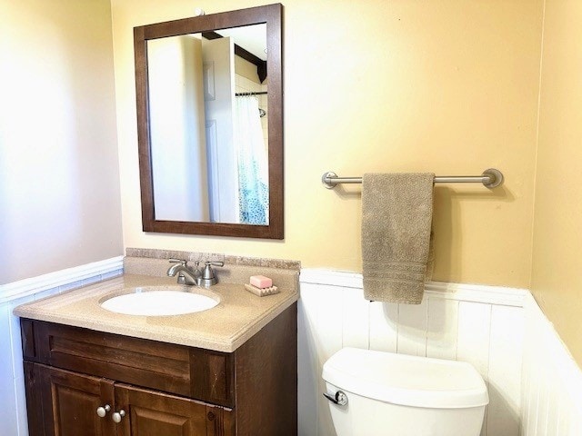 full bathroom featuring toilet, wainscoting, and vanity
