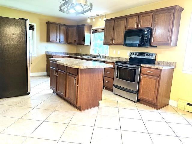 kitchen featuring a kitchen island, baseboards, a sink, appliances with stainless steel finishes, and light tile patterned floors