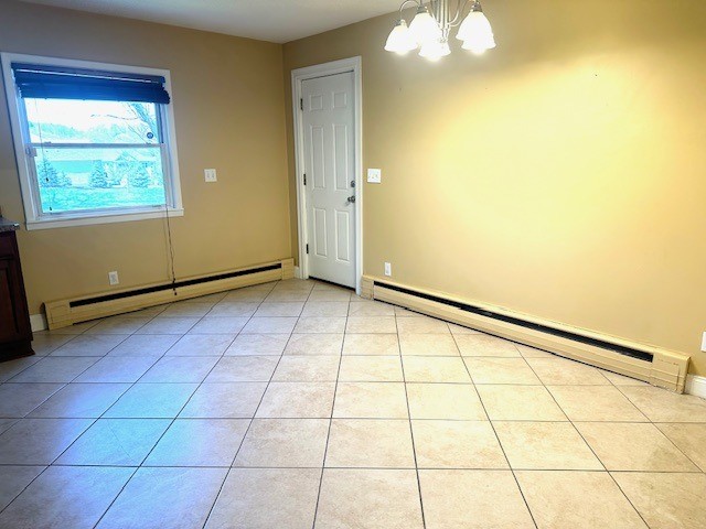 spare room with light tile patterned flooring, a notable chandelier, baseboard heating, baseboards, and a baseboard radiator