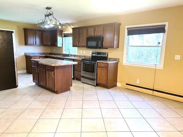 kitchen featuring a kitchen island, pendant lighting, appliances with stainless steel finishes, a sink, and a baseboard heating unit