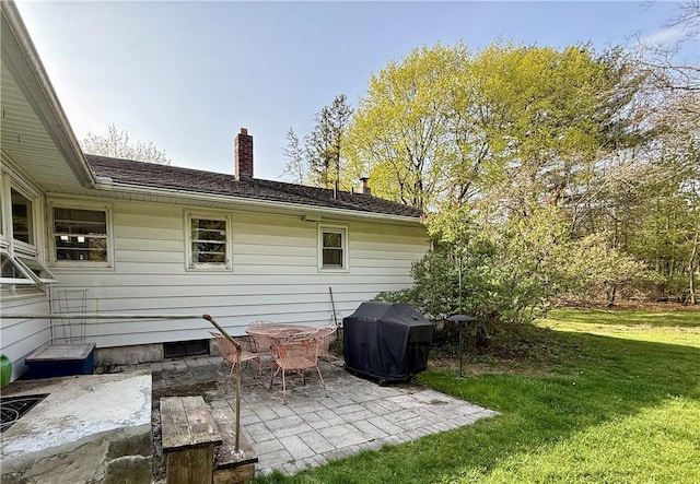 back of property with a lawn, a patio, and a chimney