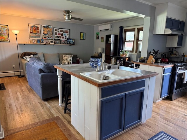 kitchen with ornamental molding, light wood-style floors, a wall mounted air conditioner, a sink, and gas stove