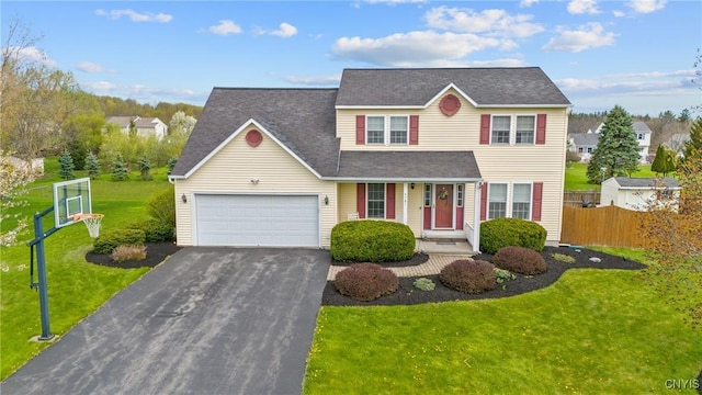 traditional home with a garage, aphalt driveway, fence, covered porch, and a front yard