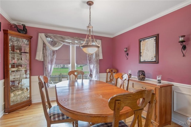 dining room with crown molding, wainscoting, and light wood-style flooring