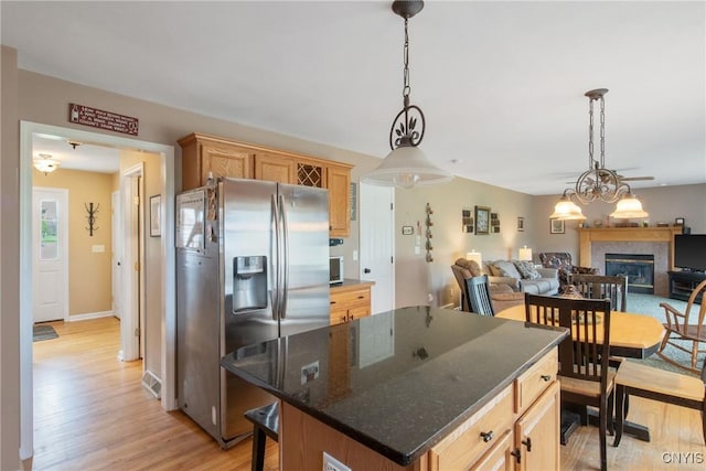 kitchen with open floor plan, light wood finished floors, a glass covered fireplace, and stainless steel fridge with ice dispenser