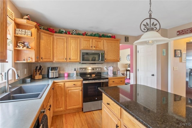 kitchen featuring pendant lighting, tasteful backsplash, a sink, light wood-style flooring, and stainless steel appliances