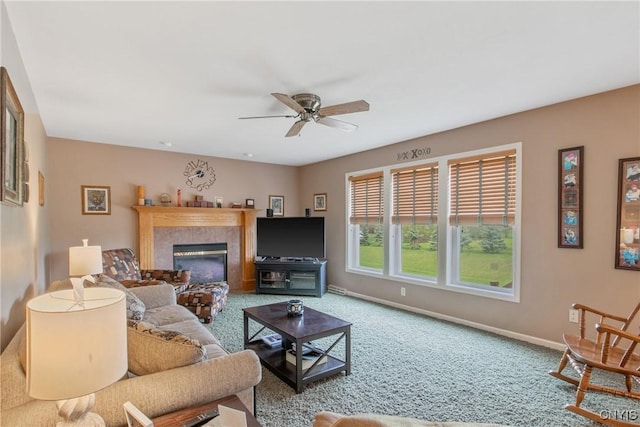 living room featuring baseboards, ceiling fan, a fireplace, and carpet flooring