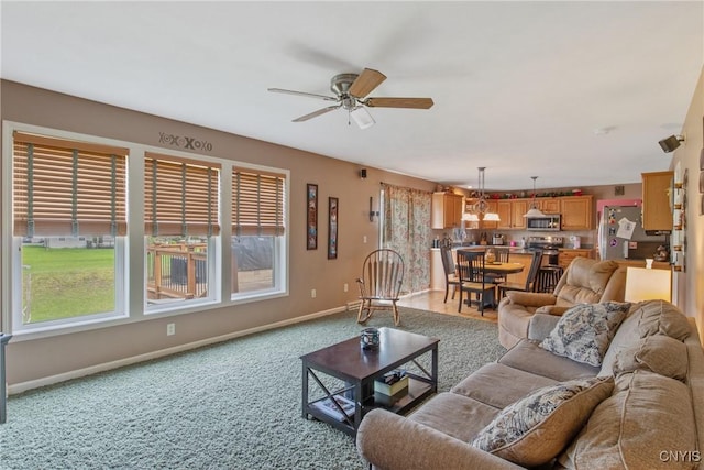living room featuring baseboards, carpet, and a ceiling fan