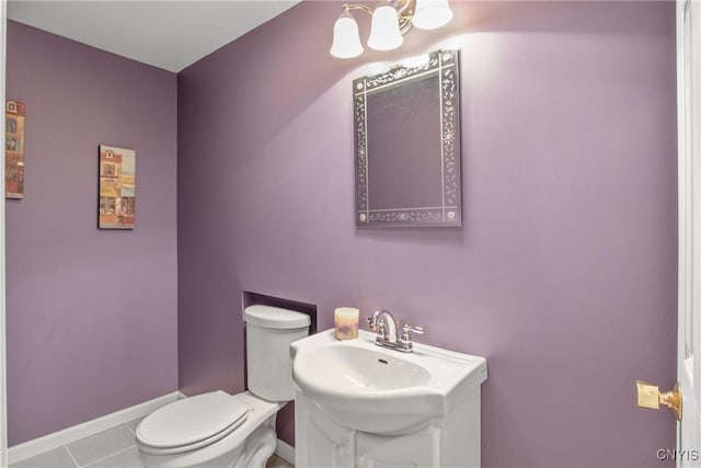half bathroom with tile patterned flooring, baseboards, toilet, and vanity
