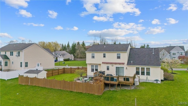 rear view of property with a fenced backyard, a yard, a residential view, and a deck