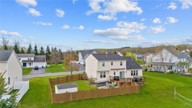 back of property featuring a lawn, a deck, a residential view, and a fenced backyard