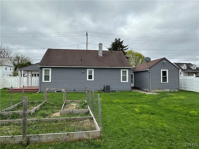 rear view of property with central air condition unit, a yard, fence, and a garden
