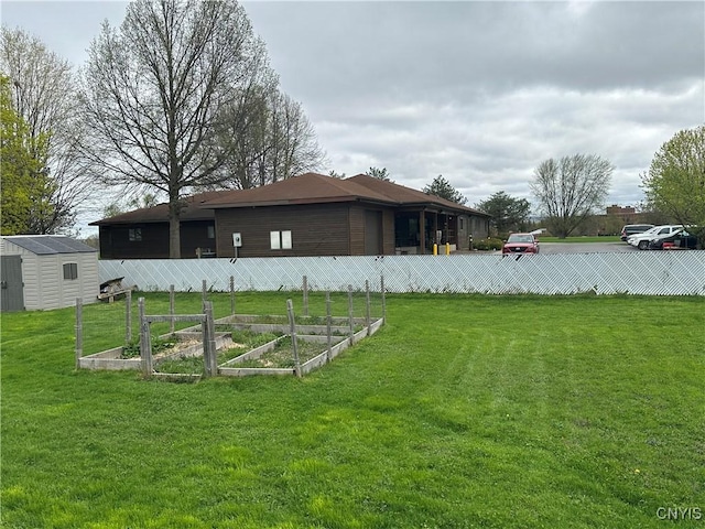 view of yard with an outdoor structure, a shed, a vegetable garden, and fence