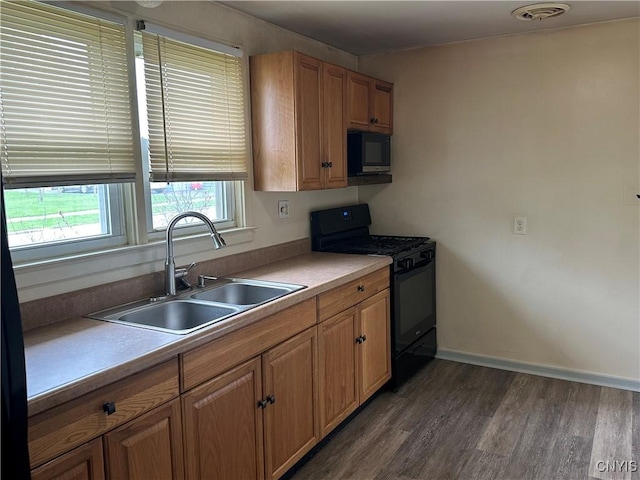 kitchen with dark wood-style flooring, visible vents, a sink, light countertops, and black appliances