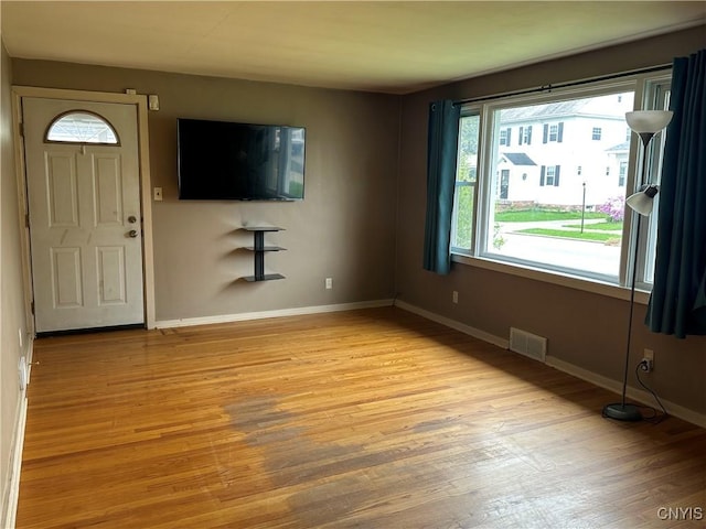 unfurnished living room with visible vents, light wood-style floors, and baseboards
