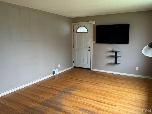 foyer entrance with light wood-type flooring, baseboards, and visible vents