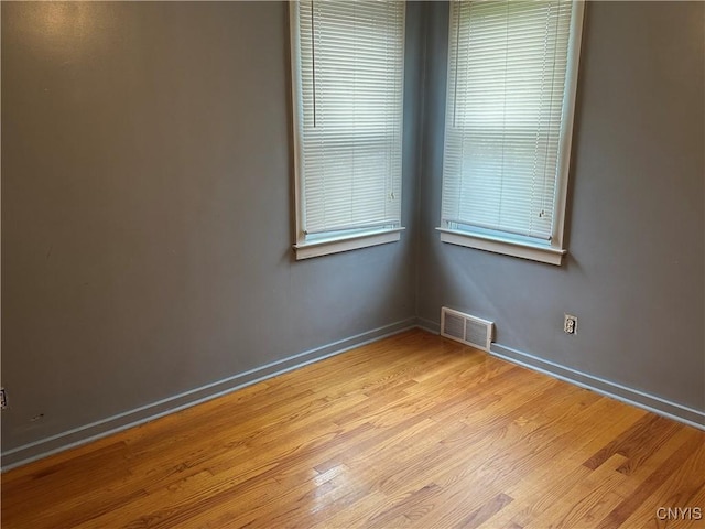 unfurnished room with visible vents, baseboards, and wood finished floors
