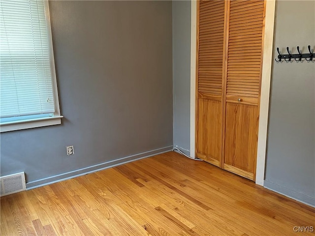 unfurnished bedroom featuring baseboards, a closet, light wood finished floors, and visible vents