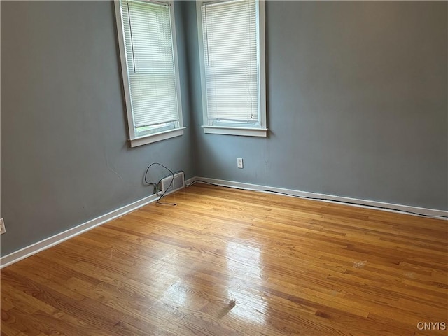 empty room with baseboards, wood finished floors, and visible vents