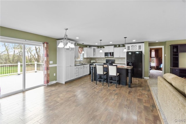 kitchen featuring a sink, black appliances, dark wood-style flooring, and open floor plan