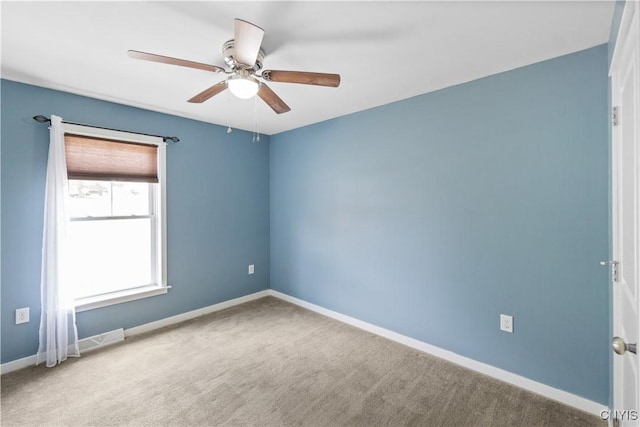 carpeted spare room featuring baseboards and ceiling fan