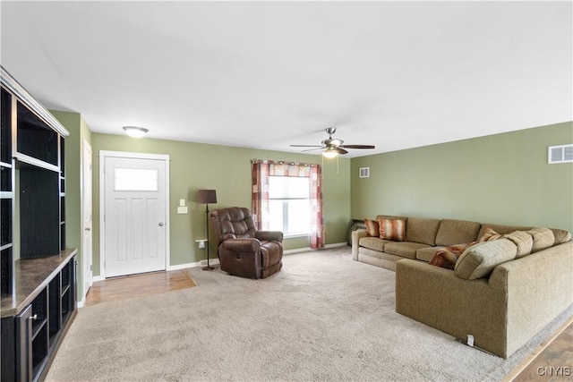 carpeted living area featuring baseboards, a ceiling fan, and visible vents